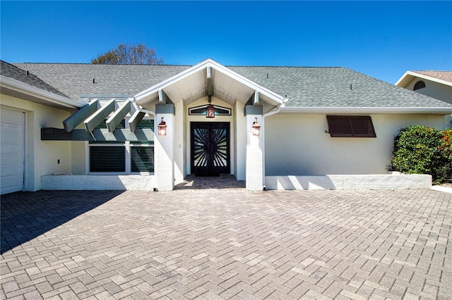 ranch-style house with a shingled roof and stucco siding