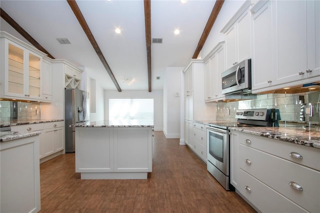 kitchen with beamed ceiling, appliances with stainless steel finishes, a kitchen island, and visible vents