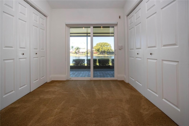 unfurnished bedroom featuring carpet floors, a water view, and access to outside