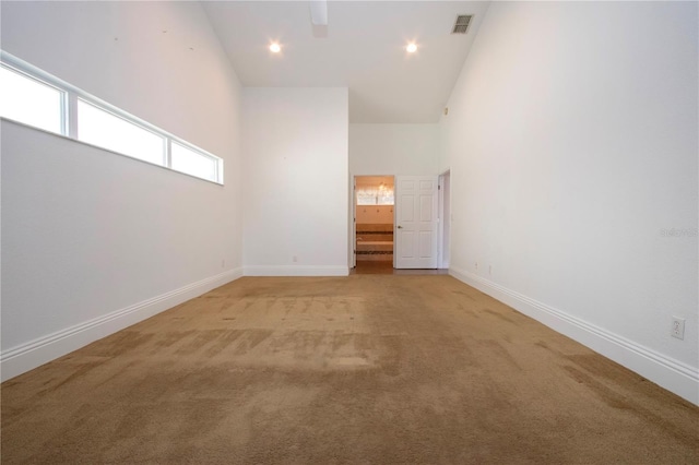 spare room featuring visible vents, baseboards, light colored carpet, recessed lighting, and high vaulted ceiling