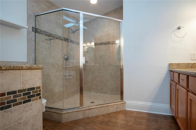 bathroom with a stall shower, vanity, ceiling fan, and wood tiled floor