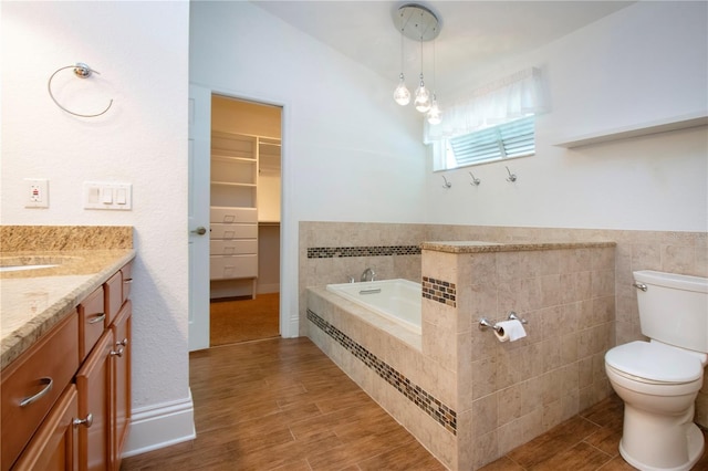 bathroom with a garden tub, toilet, wood finished floors, and vanity