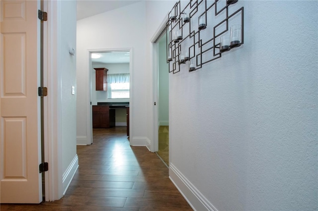 hall featuring dark wood-type flooring and baseboards