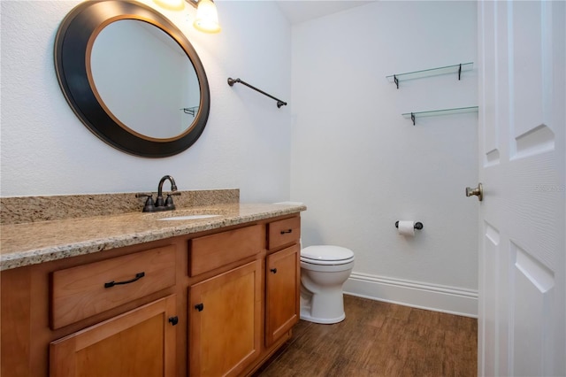 bathroom with baseboards, toilet, wood finished floors, and vanity