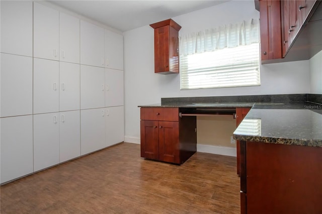 kitchen featuring white cabinets, wood finished floors, and baseboards