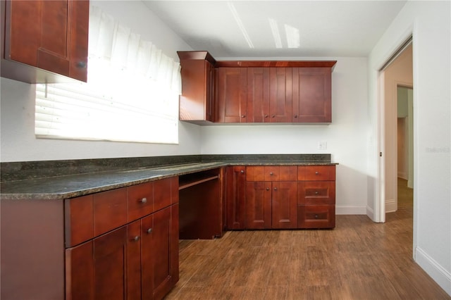 kitchen featuring dark wood-type flooring, baseboards, and reddish brown cabinets