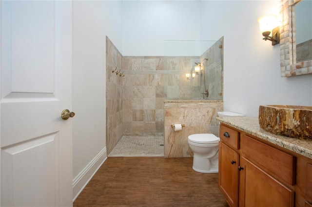 bathroom featuring a walk in shower, toilet, vanity, and wood finished floors