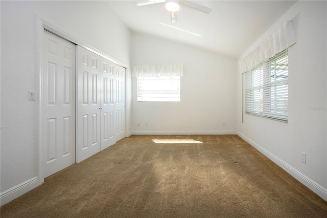 unfurnished bedroom with lofted ceiling, carpet flooring, a ceiling fan, and baseboards