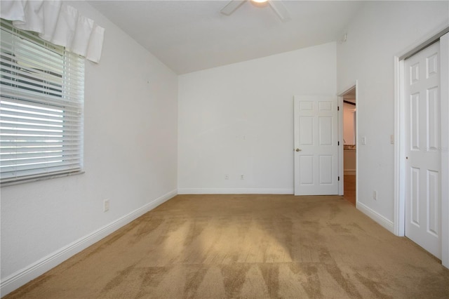 unfurnished bedroom featuring ceiling fan, baseboards, carpet, lofted ceiling, and a closet