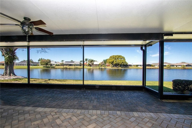 unfurnished sunroom with a wealth of natural light, ceiling fan, and a water view