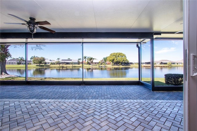 unfurnished sunroom with a water view and ceiling fan