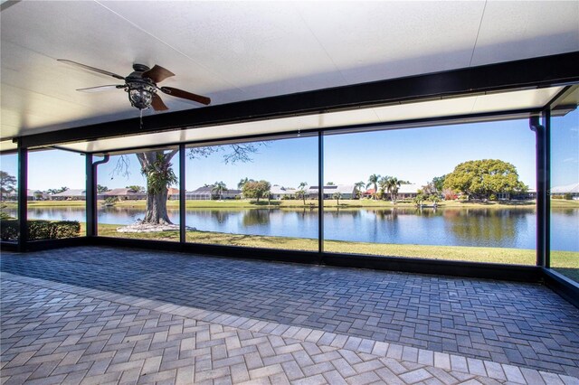 unfurnished sunroom featuring a water view and ceiling fan