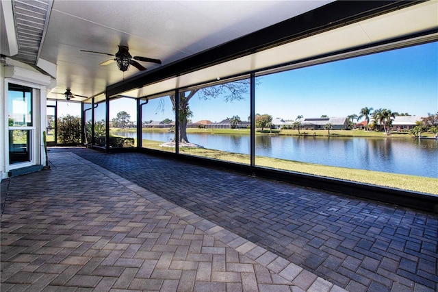 unfurnished sunroom featuring a water view and a ceiling fan