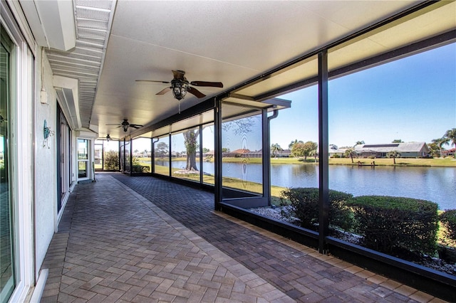 unfurnished sunroom with a ceiling fan and a water view