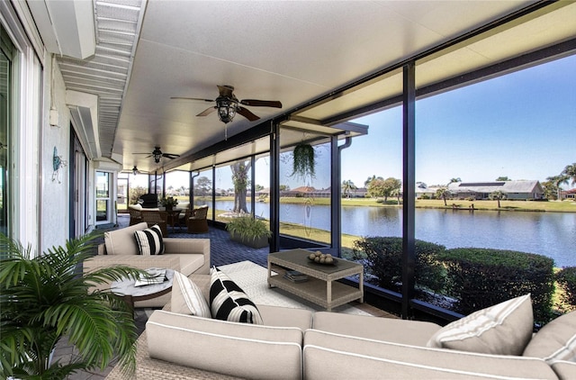 sunroom with ceiling fan and a water view