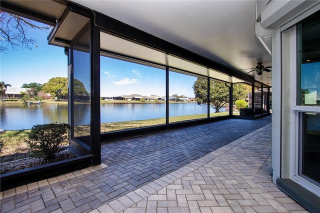 unfurnished sunroom with a water view and ceiling fan