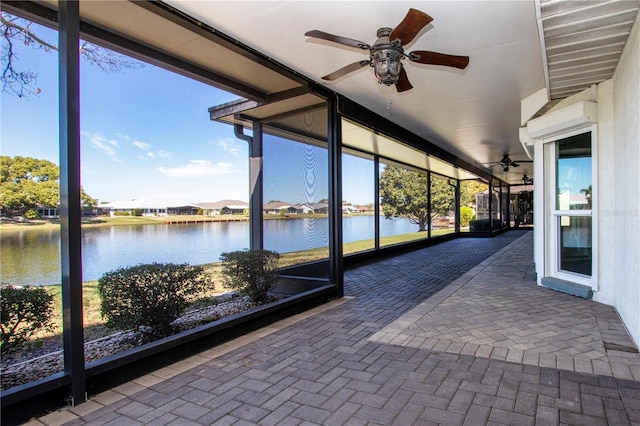 unfurnished sunroom with plenty of natural light, a water view, and ceiling fan