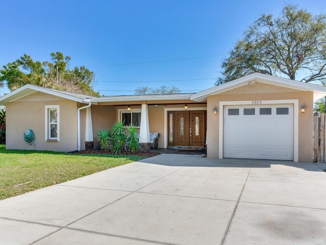 ranch-style home featuring stucco siding, a front yard, an attached garage, and driveway