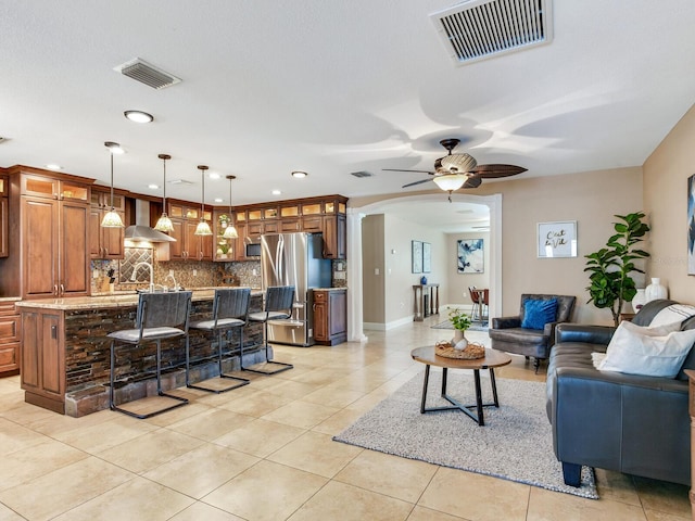 living room featuring light tile patterned floors, visible vents, arched walkways, and a ceiling fan