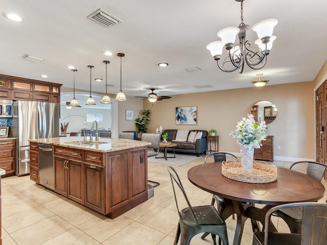 kitchen with visible vents, pendant lighting, a kitchen island with sink, a sink, and appliances with stainless steel finishes