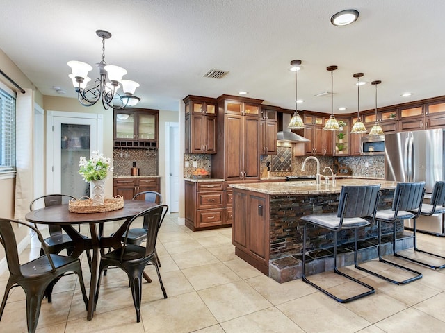 kitchen featuring a center island with sink, visible vents, stainless steel appliances, decorative backsplash, and glass insert cabinets