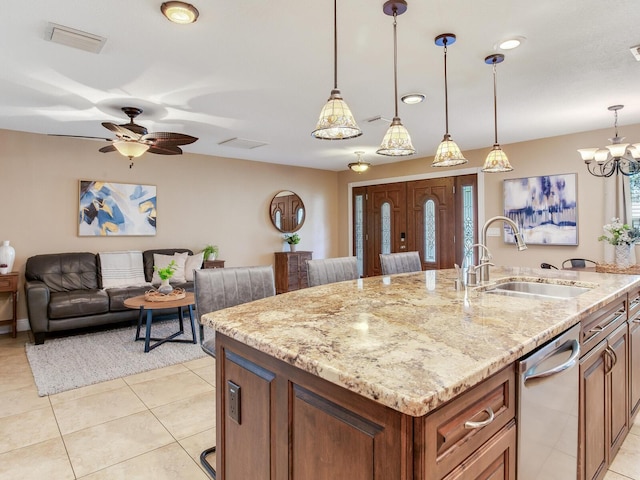 kitchen featuring visible vents, a sink, light stone counters, light tile patterned flooring, and a kitchen island with sink