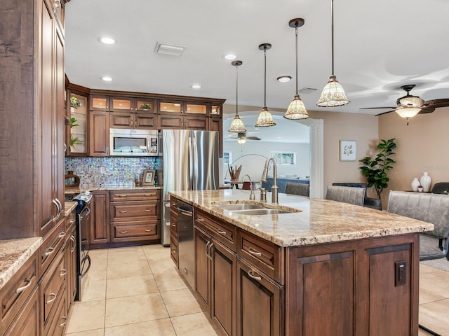 kitchen with open floor plan, a center island with sink, light tile patterned flooring, stainless steel appliances, and a sink