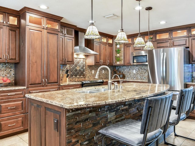 kitchen featuring visible vents, a sink, appliances with stainless steel finishes, wall chimney range hood, and light tile patterned floors