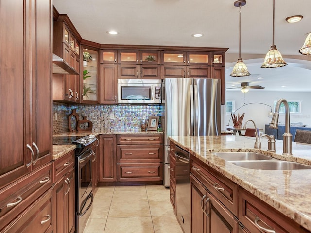 kitchen with light tile patterned flooring, a sink, stainless steel appliances, pendant lighting, and tasteful backsplash