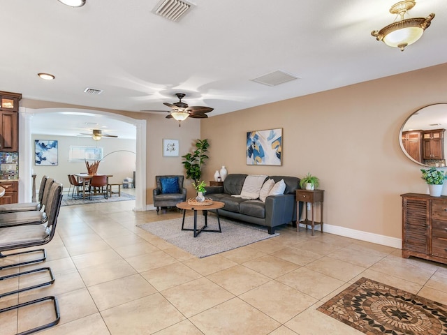 living area featuring arched walkways, visible vents, baseboards, and light tile patterned flooring