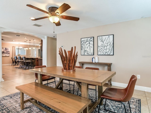 dining area featuring visible vents, ornate columns, baseboards, light tile patterned flooring, and arched walkways