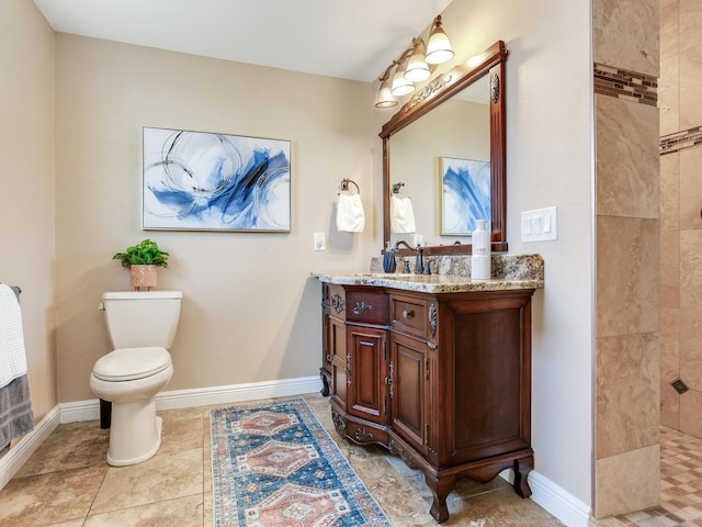 bathroom with a tile shower, toilet, vanity, and baseboards