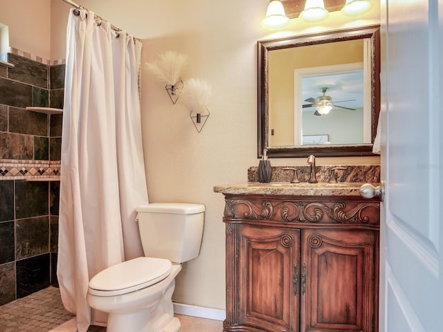 bathroom with vanity, baseboards, a tile shower, ceiling fan, and toilet