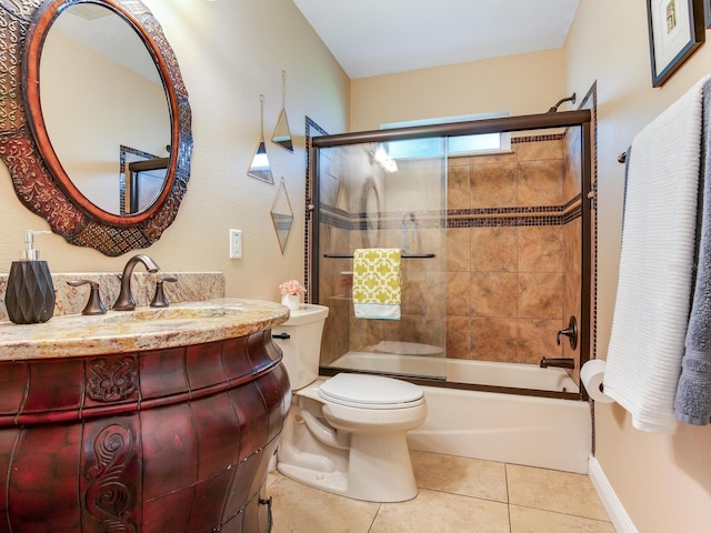 bathroom featuring baseboards, toilet, shower / bath combination with glass door, tile patterned floors, and vanity