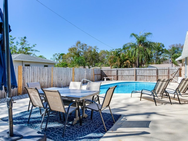 view of swimming pool with a fenced in pool, a patio, a fenced backyard, and outdoor dining space