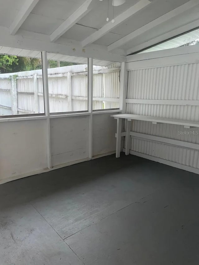unfurnished sunroom featuring beamed ceiling