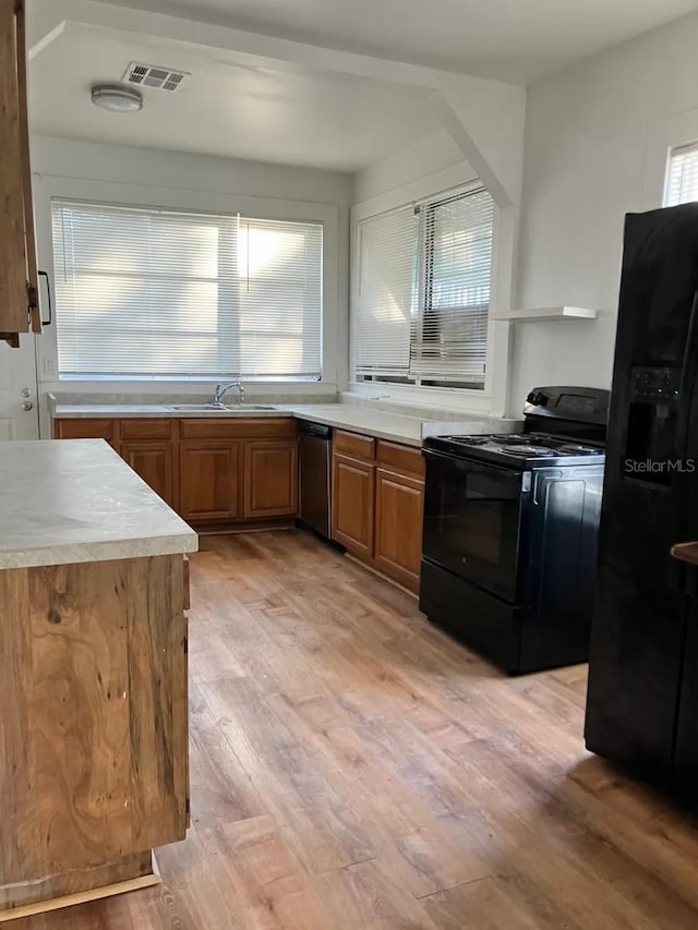 kitchen featuring brown cabinetry, black appliances, light wood-style flooring, light countertops, and visible vents