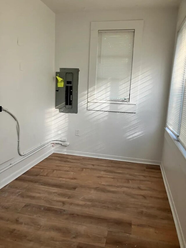 interior space featuring electric panel, baseboards, and wood finished floors