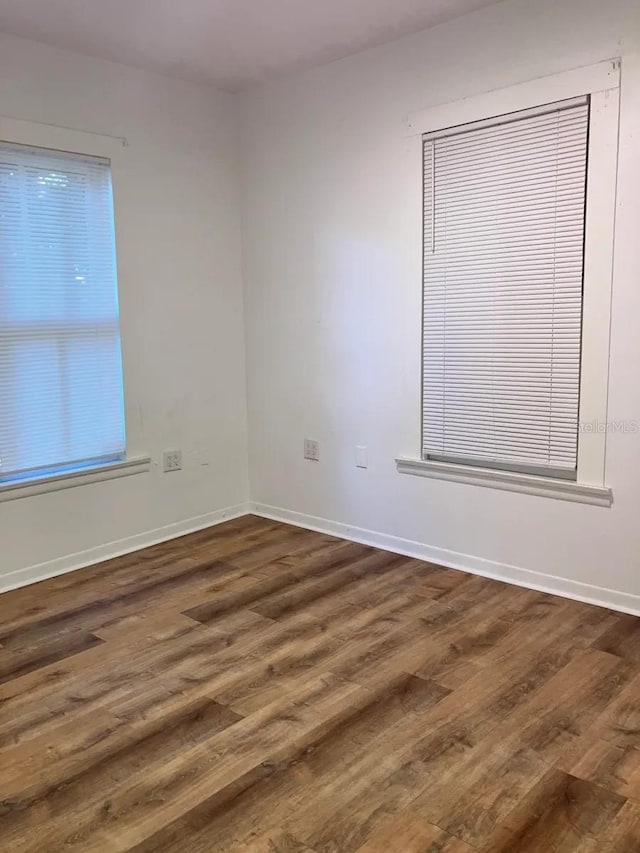 unfurnished room with baseboards and dark wood-style flooring
