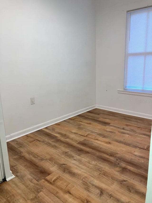 unfurnished room with baseboards and wood finished floors