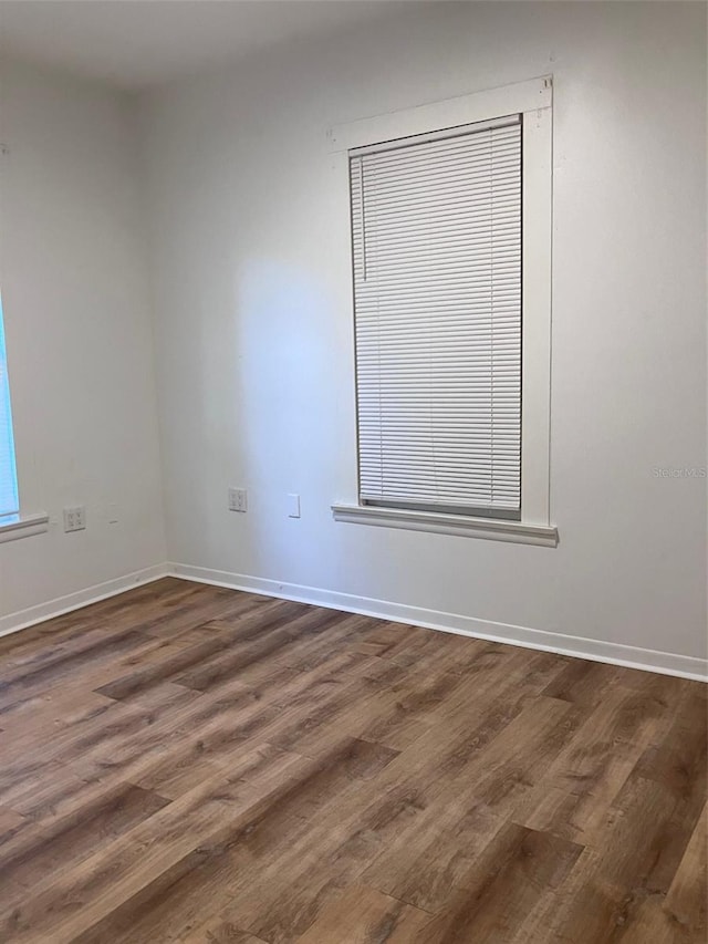 unfurnished room featuring baseboards and dark wood-style flooring