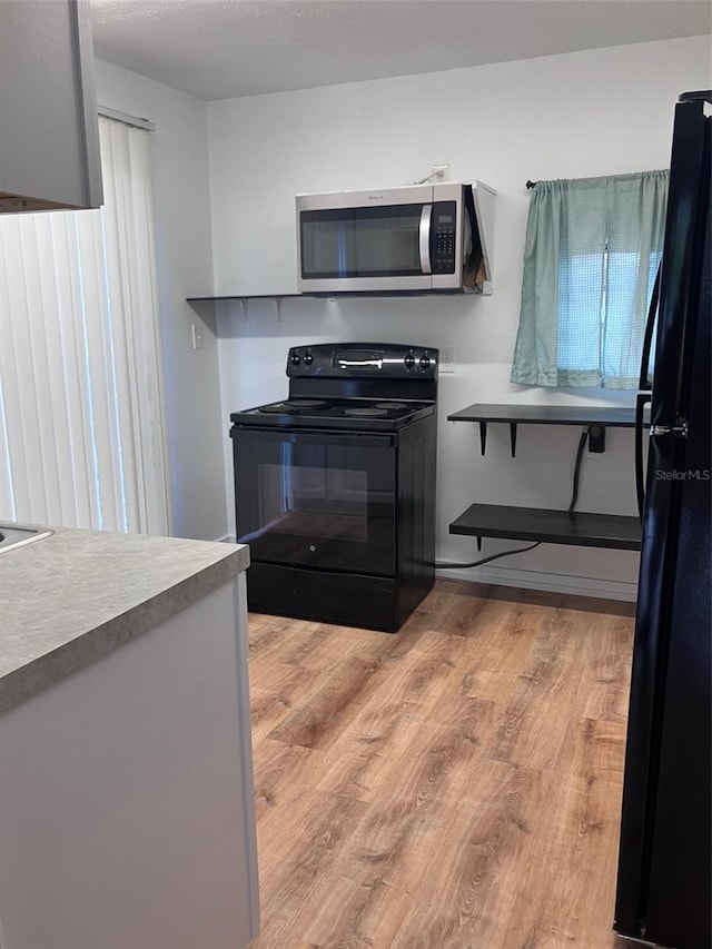 kitchen with light wood-type flooring and black appliances