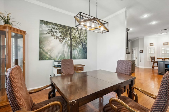 dining space featuring wood finished floors, baseboards, and ornamental molding