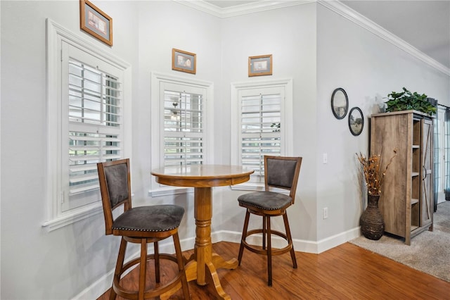 dining space featuring wood finished floors, baseboards, breakfast area, and ornamental molding