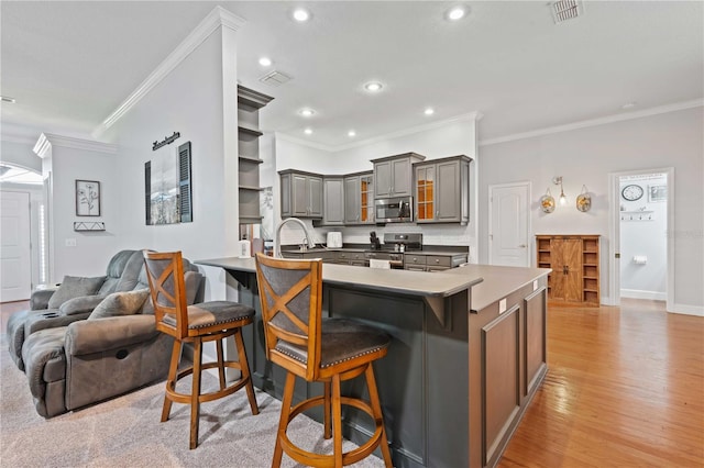 kitchen with visible vents, gray cabinets, stainless steel appliances, a peninsula, and a breakfast bar area