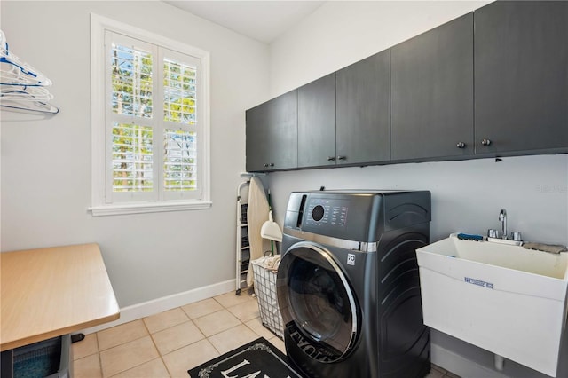 laundry area featuring baseboards, light tile patterned floors, cabinet space, washer / clothes dryer, and a sink