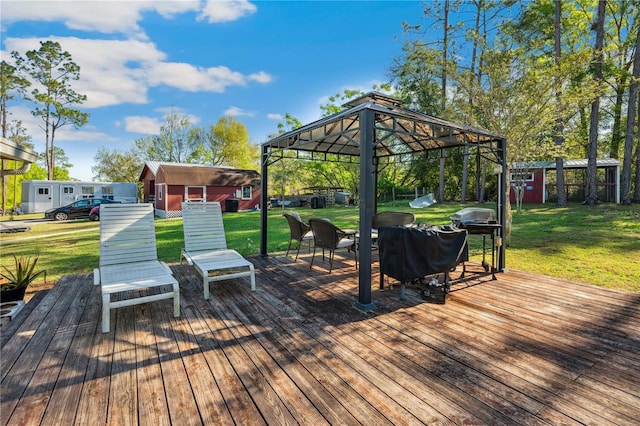 wooden deck with a gazebo, an outbuilding, a storage unit, and a lawn