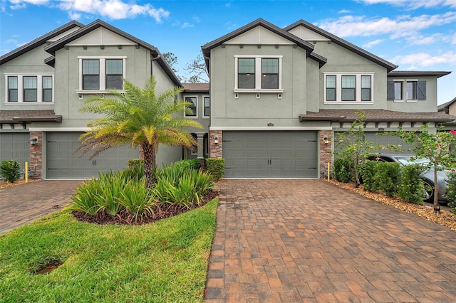 view of front of property with decorative driveway, a garage, and stucco siding