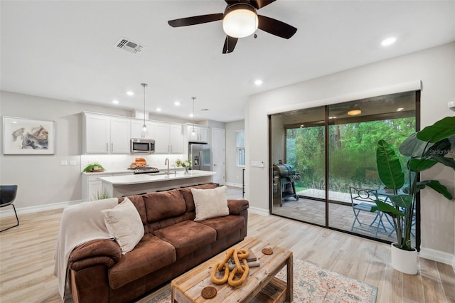 living room with light wood finished floors, visible vents, recessed lighting, and baseboards