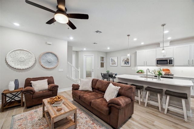 living area featuring visible vents, baseboards, recessed lighting, stairs, and light wood-style floors